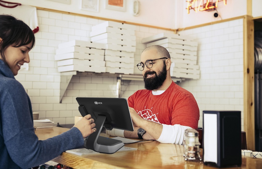 a man and woman looking at NCR checkout monitor