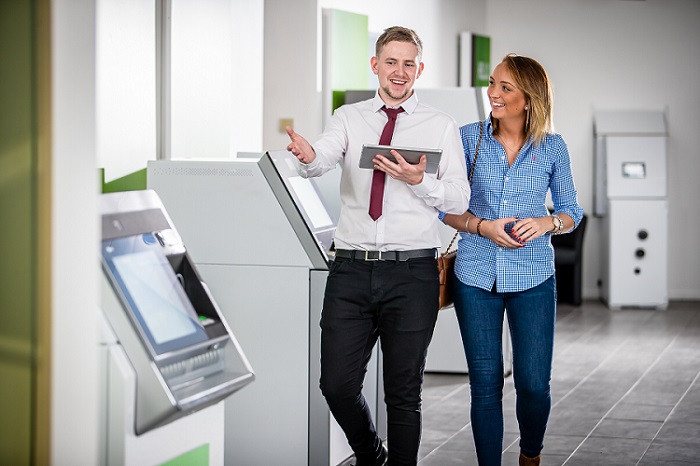 A man and a woman standing surrounded by ATMs