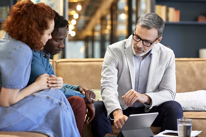 A businessman is discussing over digital tablet with two people