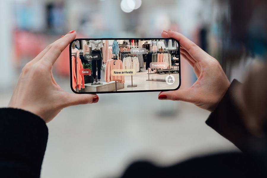Female hand holding smartphone using augmented reality application to check special sale price in retail fashion store. Shopping with innovative technology makes our life easier. Mockup image for woman using smartphone.