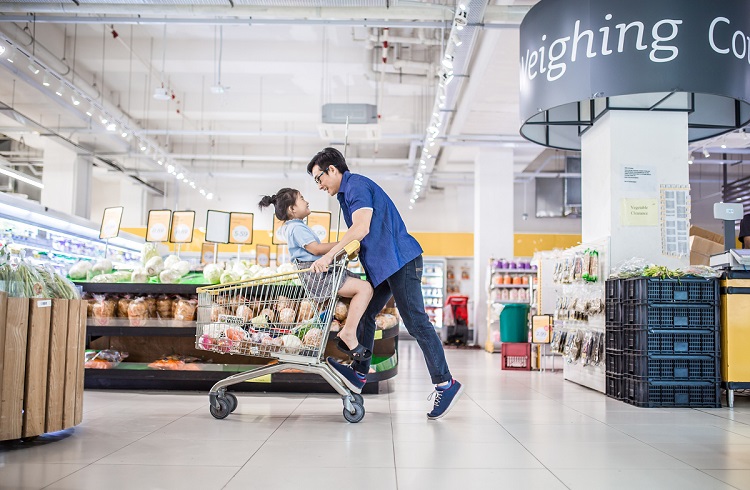 An Asia Chinese girl sitting in a shopping cart being pushed by her father. They having fun in supermarket.