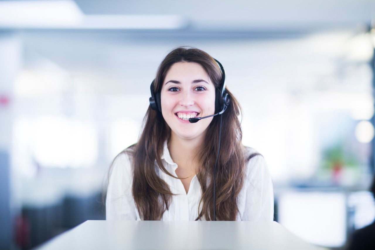 young female woman girl smiling with headset on in office digital connected services
