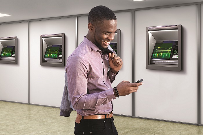 a person looking at the phone, with series of SelfServ 80 NCR ATMs in the background