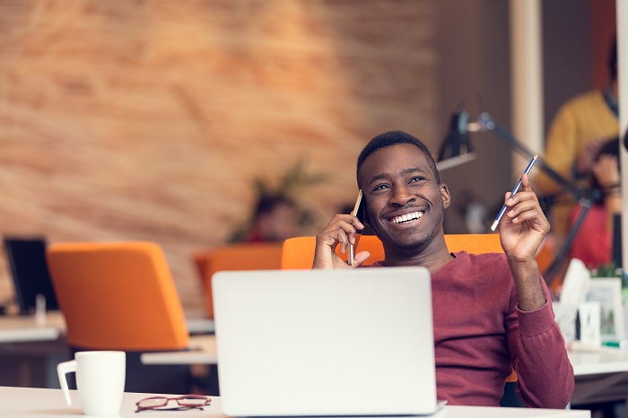 African American businessman on the phone sitting at the computer in his startup office