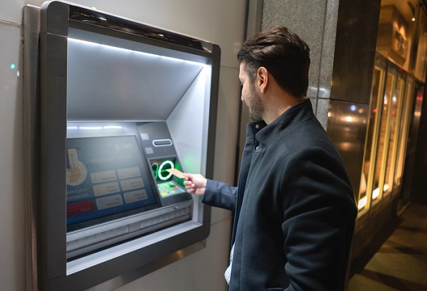 Man withdrawing money at a cash point in the streets of New York. **DESIGN ON SCREEN AND CREDIT CARD WERE MADE FROM SCRATCH BY US)