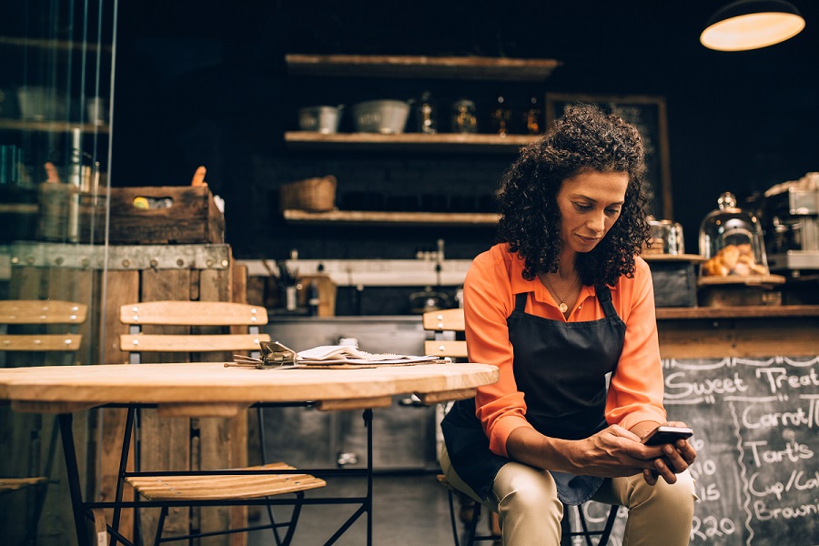 Shot of a mature woman using a mobile phone while working in a coffee shop