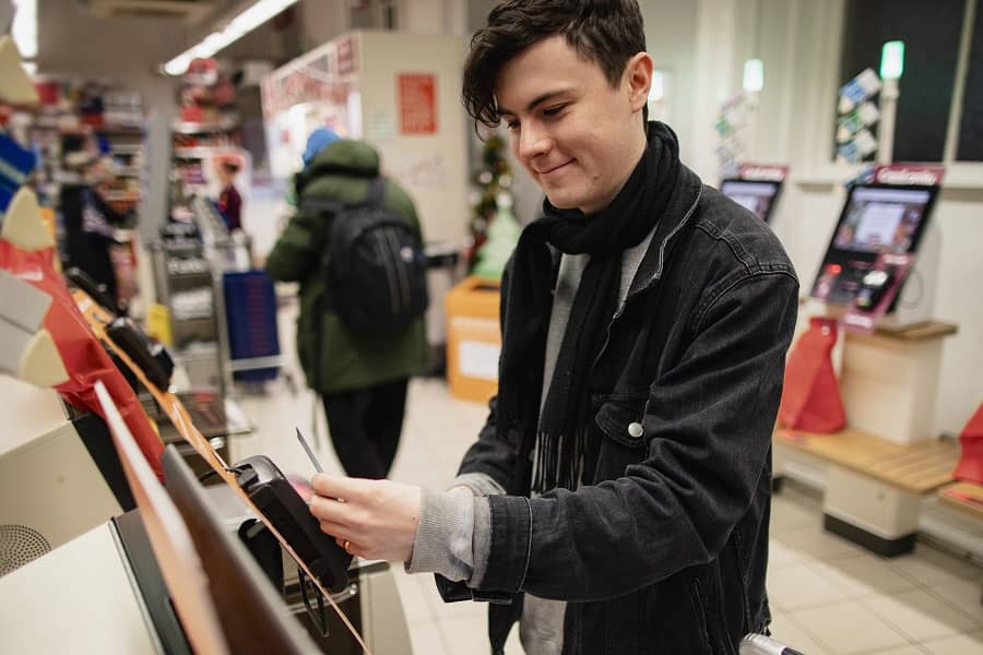 Young man using NCR self-serv checkout system