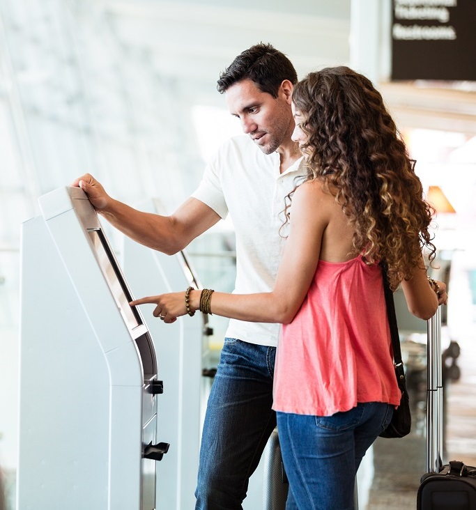 Couple using automated check-in machine at airport