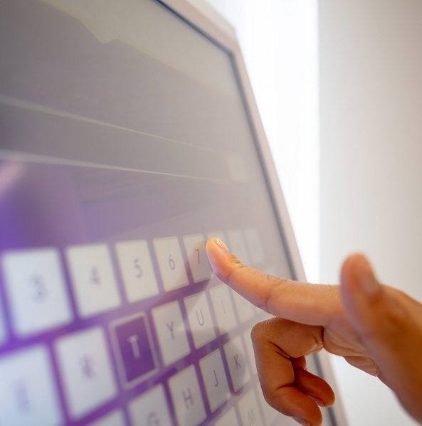 Close-up of woman using touch screen monitor to check-in online