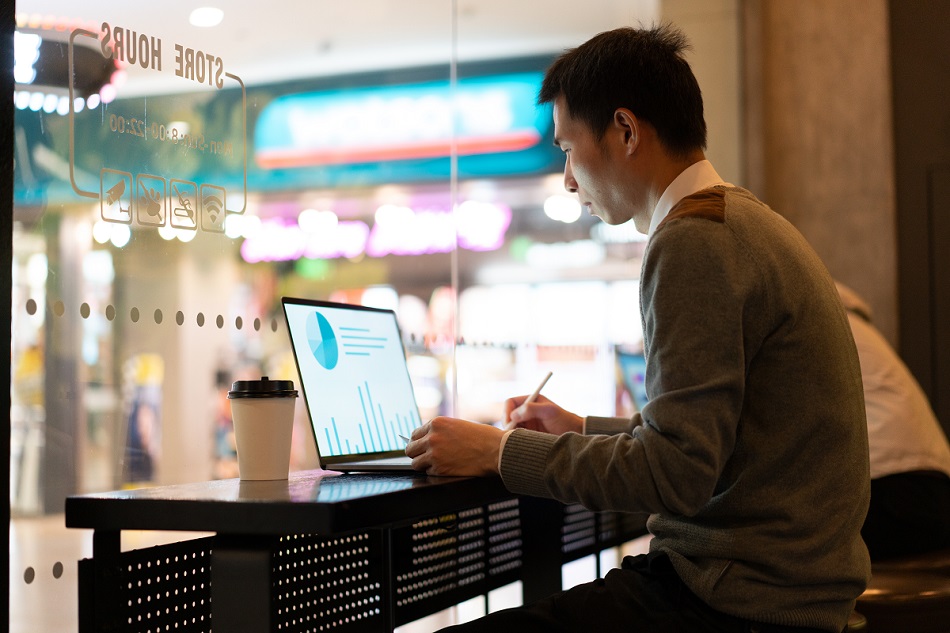 Asian man using laptop in shop