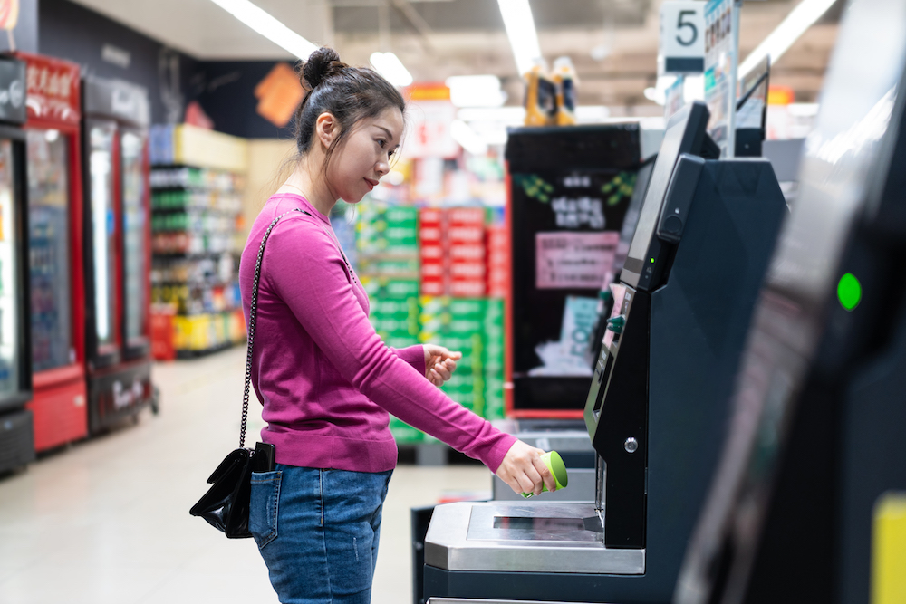 A woman is checkouting by automatic payment machine in a supermarket