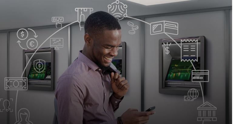 A man smiling at a phone surrounded by 3 ATM machines